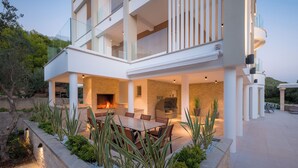 A modern two-story house with a patio area featuring a dining table and chairs, a fireplace, and a built-in grill. - Villa 01 - Apartment 4 (4 + 2, 2nd floor) (Promajna)