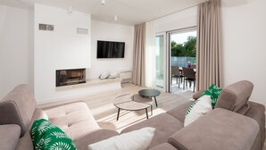 A modern living room with a fireplace, a flat-screen TV, and a dining area with outdoor seating. - Villa 01 - Apartment 4 (4 + 2, 2nd floor) (Promajna)