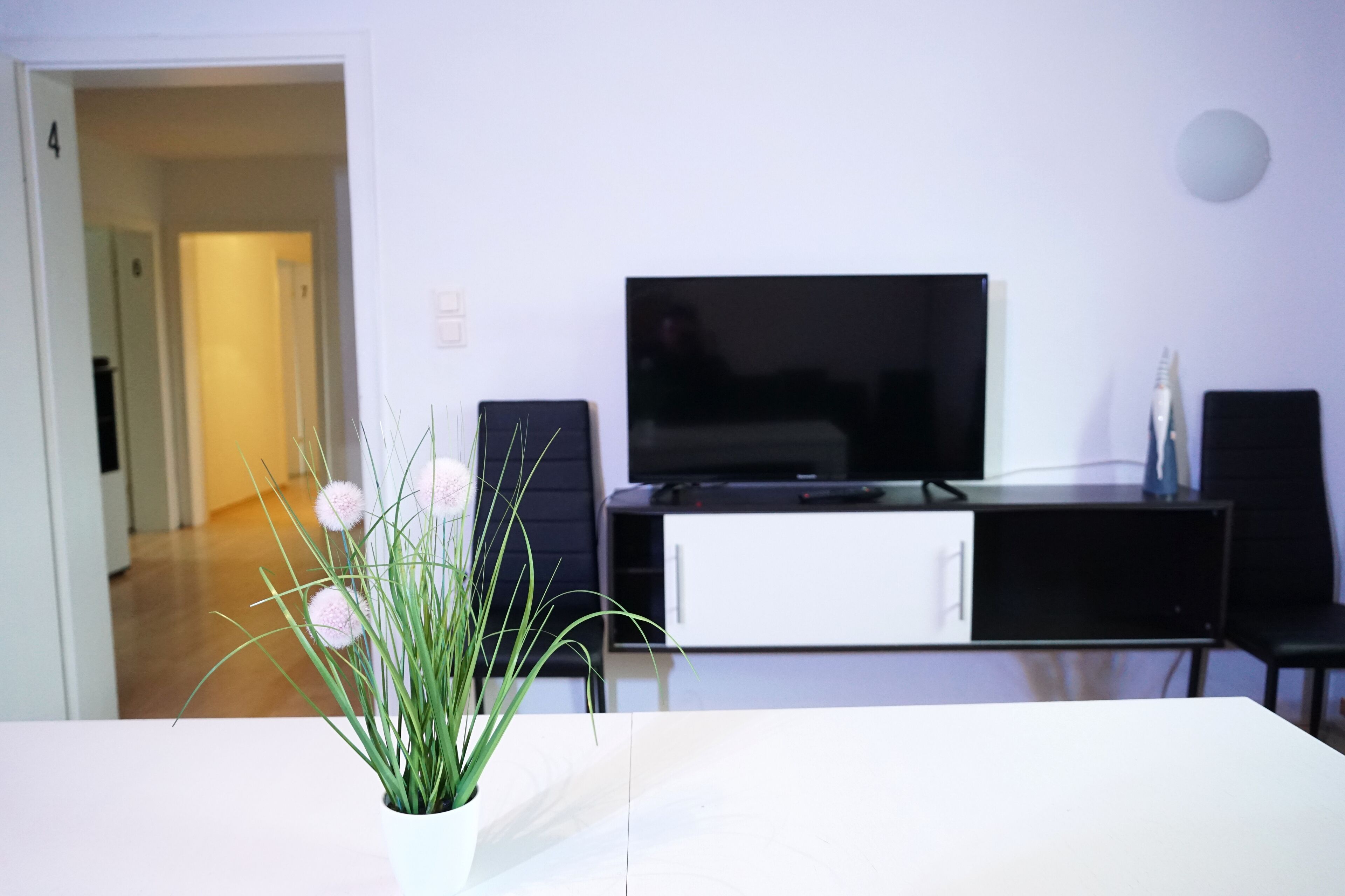 Ein Wohnzimmer mit einem Flachbildfernseher, einem weißen Schrank und einem Topfpflanzen.