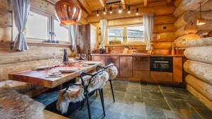 L’intérieur d’un chalet en bois comprend un coin repas, une cuisine et de grandes fenêtres.