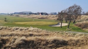 Un parcours de golf avec un bunker de sable, un drapeau et un chemin.