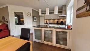 Une cuisine moderne dotée d’un îlot central, de meubles blancs et d’un éclairage suspendu.