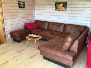 Ein braunes, ledernes Ecksofa mit einem Couchtisch aus Holz in einem Raum mit Holzwänden und Holzboden.