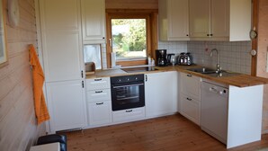 A kitchen with white cabinets, a wooden countertop, a sink, a stove, and a dishwasher. - Wood-semidetached house, ideal for 2 families (Brodersby)