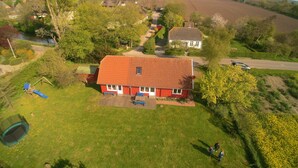 A residential area with a red-roofed house, a playground, and a field. - Wood-semidetached house, ideal for 2 families (Brodersby)