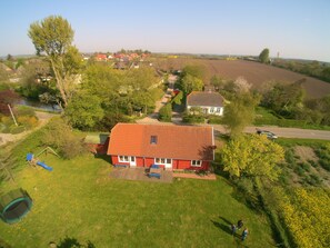 Ein Wohngebiet mit einem rotem Haus, einem Spielplatz und einem Feld.