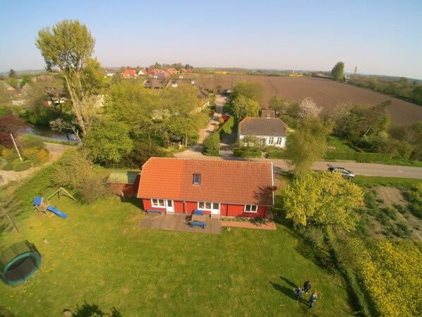 Ein Wohngebiet mit einem rotem Haus, einem Spielplatz und einem Feld.