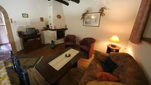 Ein gemütliches Wohnzimmer mit einer Couch, Sesseln, einem Couchtisch, einem Kamin und einem Fernseher.