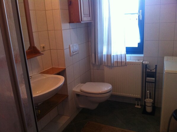 A small bathroom with a white sink, toilet, and a window with curtains. - Cozy cane roof house near the Bodden, practically furnished, sauna, max.7pers (Mecklenburg-Vorpommern)