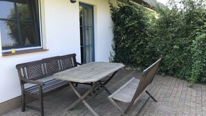 Un espace extérieur aménagé avec une table et des bancs, une fenêtre et une porte.