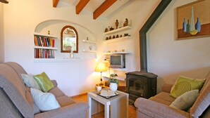 A cozy living room with two sofas, a small table with a lamp, a bookshelf, a fireplace, and a painting on the wall. - Rural tranquillity at the foot of the Tramuntana, pool with panoramic views (Campanet)