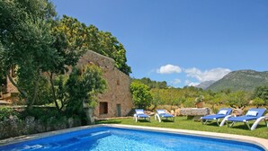 A clear blue pool with lounge chairs, surrounded by greenery and a stone building. - Rural tranquillity at the foot of the Tramuntana, pool with panoramic views (Campanet)