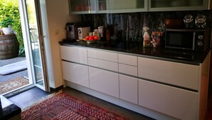 Une cuisine moderne avec des meubles blancs, un plan de travail noir et une porte vitrée donnant sur un patio.