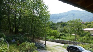 A car parked on a gravel path surrounded by lush greenery and a stone wall. - Apartment in Asturian country house, close to beach (Asturien)