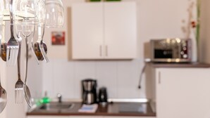 Een keuken met witte kastjes, een magnetron en een koffiezetapparaat.