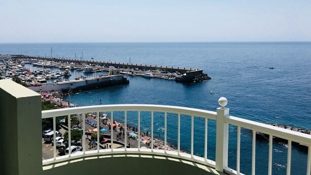 A coastal marina with boats docked, a pier extending into the water, and a balcony with a railing. - Right on the beach quiet apartment with a large terrace (Radazul)