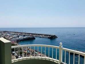 A coastal marina with boats docked, a pier extending into the water, and a balcony with a railing. - Right on the beach quiet apartment with a large terrace (Radazul)