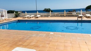 A swimming pool with a tiled deck, white lounge chairs, and a white fence. - Right on the beach quiet apartment with a large terrace (Radazul)