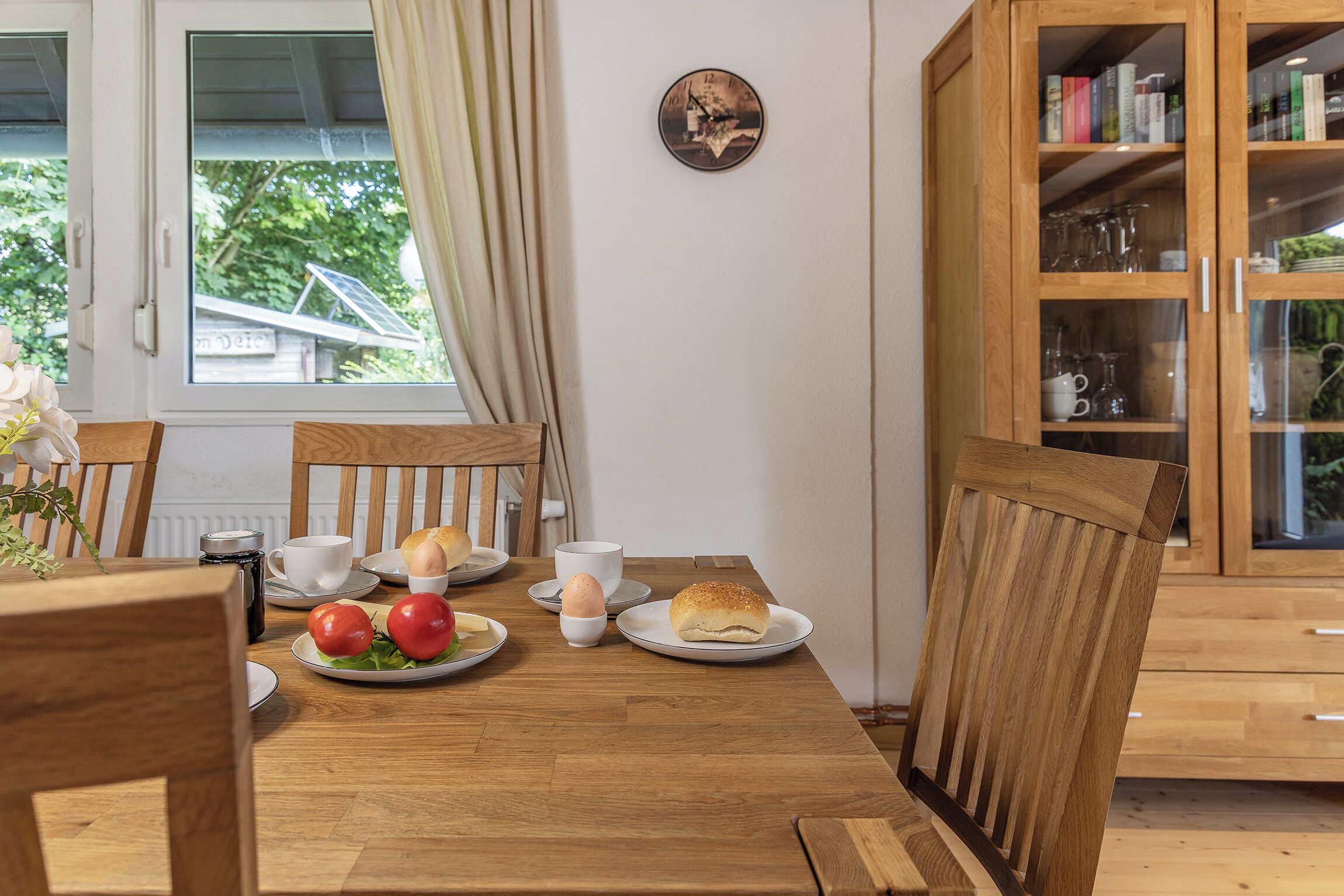 A wooden dining table with plates of food, a cup, and a saucer.