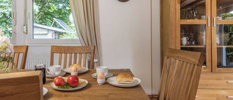 A wooden dining table with plates of food, a cup, and a saucer.