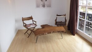 A room with a wooden bench, two chairs, a wall-mounted deer skull artwork, and a window with curtains. - Apartment with a beautiful mountain view (Garmisch-Partenkirchen)