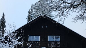 A wooden cabin with a balcony, surrounded by snow-covered trees. - Apartment with a beautiful mountain view (Garmisch-Partenkirchen)