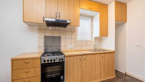 Eine kompakte Küche mit Gaskochfeld, Backofen und einem Fenster über der Spüle.