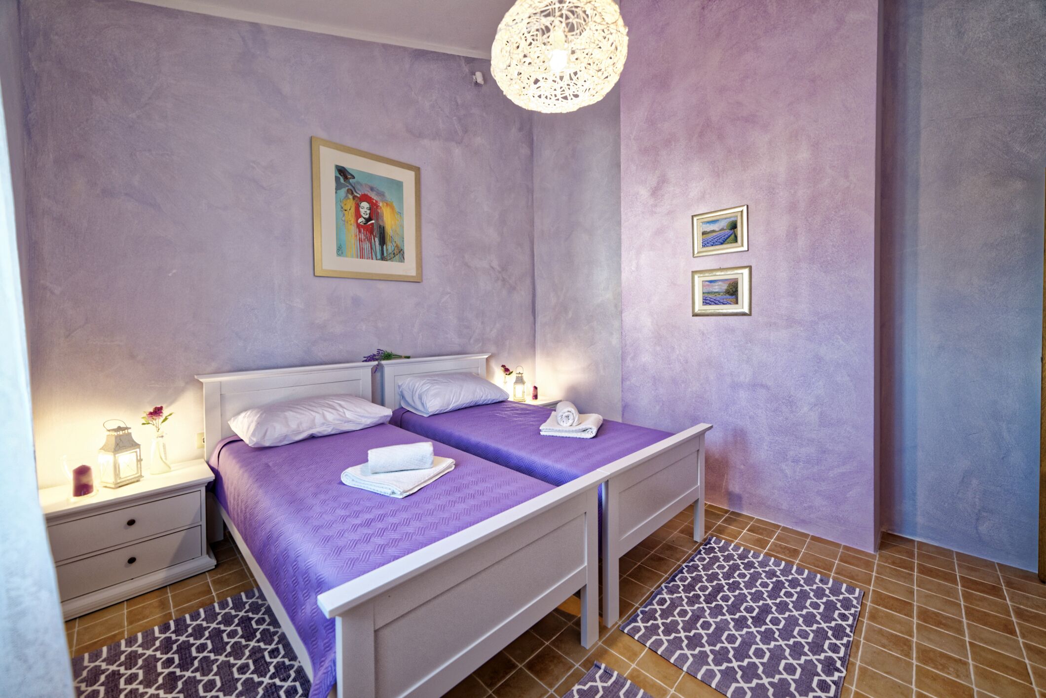 Un dormitorio con dos camas, una mesita de noche, una lámpara y un cuadro en la pared.