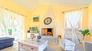 Un salon avec une cheminée, une horloge et un téléviseur.
