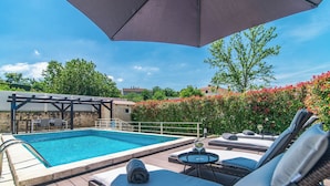 Une piscine avec des chaises longues et une pergola.