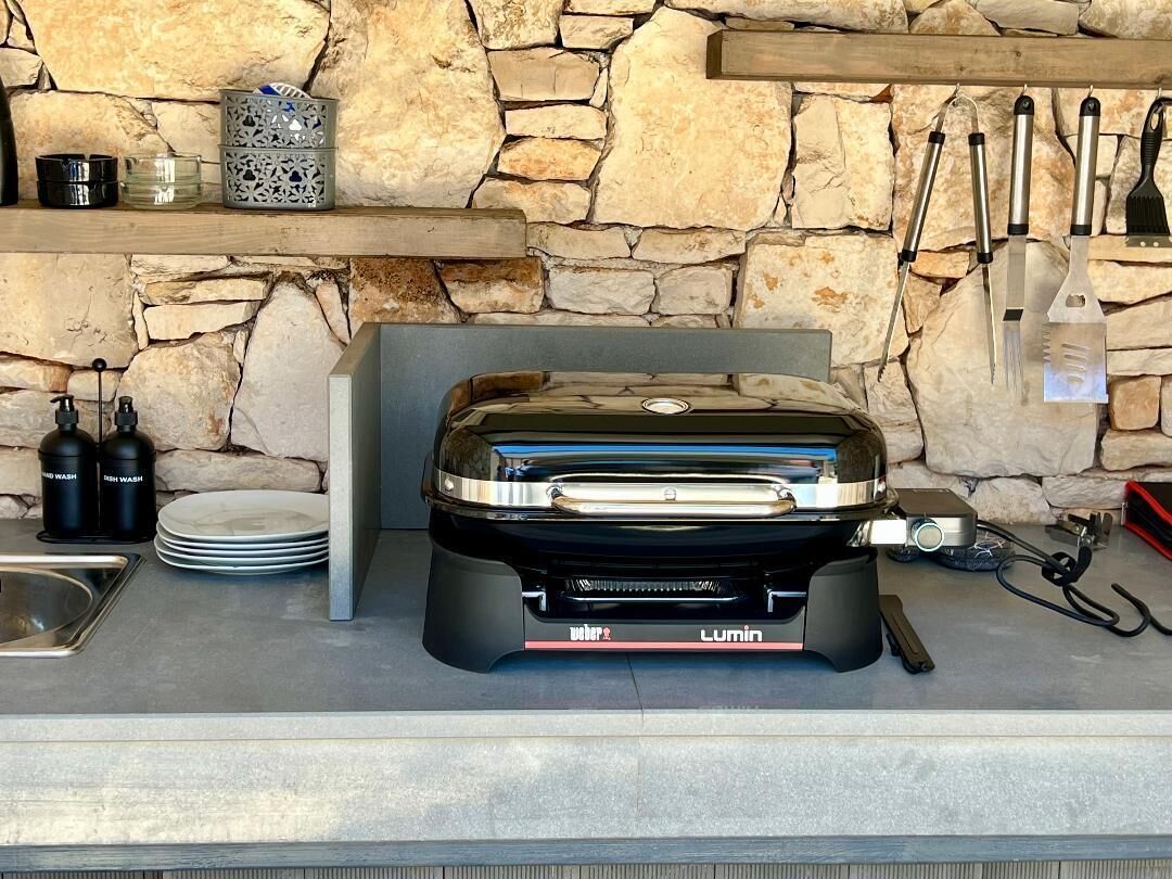 Eine Küche mit Steinwand, integriertem Grill und verschiedenen Küchenutensilien.