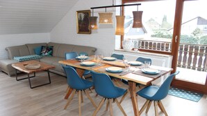 A dining area with a wooden table set for four, blue chairs, and a sofa with cushions. - modern, very spacious apartment in the immediate vicinity of the Center Parcs (Medebach)