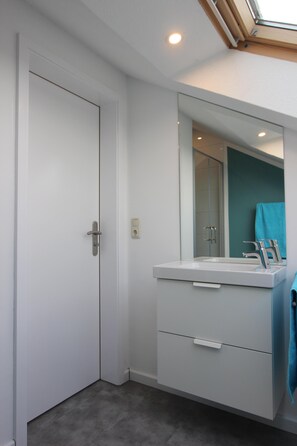 A bathroom with a white vanity, a mirror, and a shower. - modern, very spacious apartment in the immediate vicinity of the Center Parcs (Medebach)