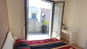 A bedroom with a bed, a desk, and a sliding glass door leading to an outdoor area. - Nice vacation apartment in S. Alessandro-Riva del Garda. (riva del garda)