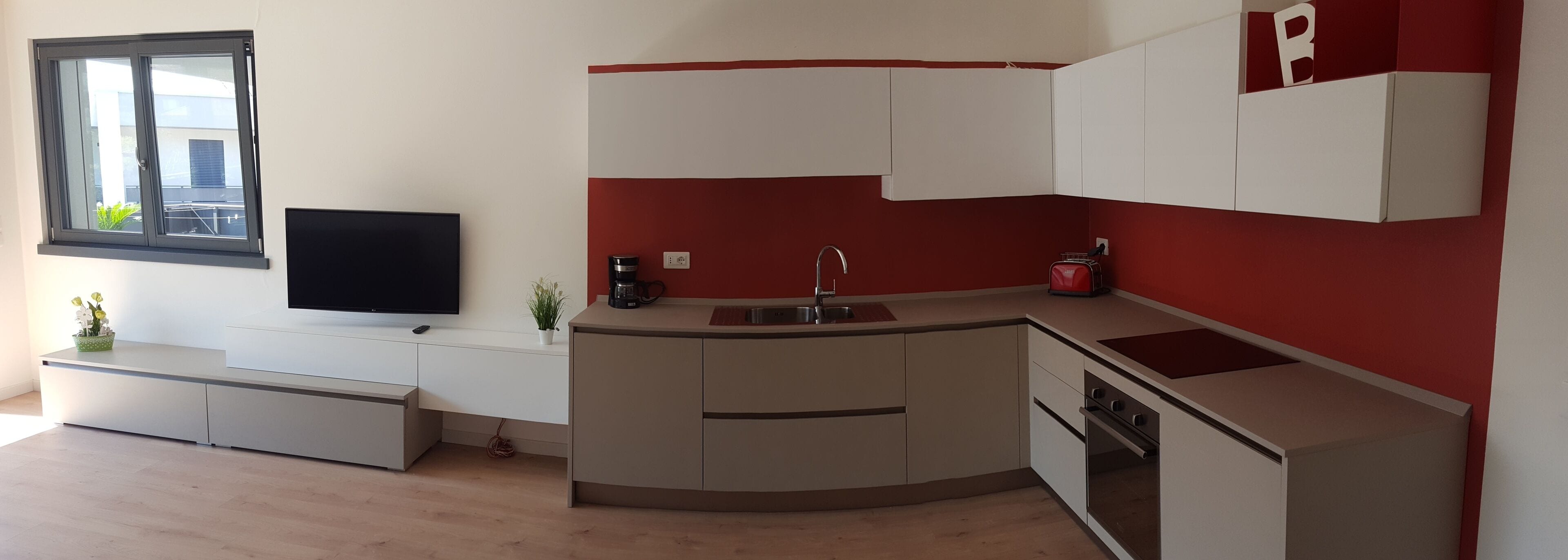 Cocina compacta con televisión integrada, un lavamanos y una estufa.