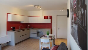 A compact kitchen with a dining area, a coffee machine, and a red accent wall. - Nice vacation apartment in S. Alessandro-Riva del Garda. (riva del garda)