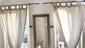 Ein Schlafzimmer mit einem Bett, einem großen Spiegel und Vorhängen.