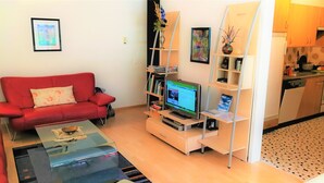 A living room with a red sofa, a coffee table, a TV, and a bookshelf.
