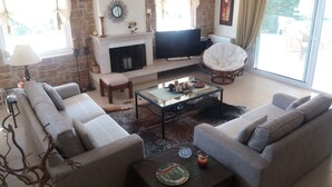 Ein Wohnzimmer mit Kamin, Fernseher und einer gemütlichen Sitzecke.