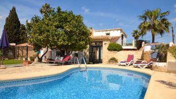 A swimming pool with lounge chairs and a tree in the background.