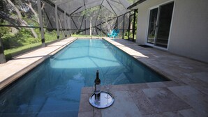 A covered swimming pool with a bottle and glasses on a tray, surrounded by a patio area with chairs and a door. - Modern villa with large pool! Free Wifi! (Venice)