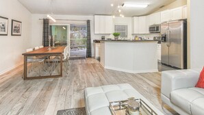 A modern kitchen with white cabinets, stainless steel appliances, and a wooden dining table. - Modern villa with large pool! Free Wifi! (Venice)