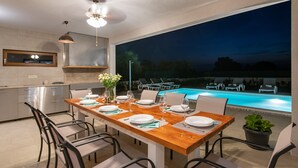 Une cuisine moderne avec un coin repas donnant sur une piscine.