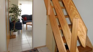 A wooden staircase leading to a living area with a sofa, a coffee table, and a potted plant. - Cozy apartment - incl. Beach chair Apr-Sep, small and quiet residential complex (Dornumersiel)