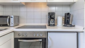Una cocina compacta con microondas, cafetera y horno.