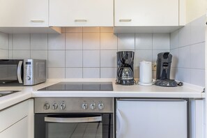 Una cucina compatta con forno a microonde, macchina del caffè e forno.