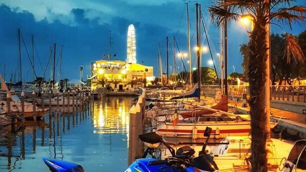 A blue motorcycle parked by a marina with boats and a building in the background. - Appartamentino Rustico in Villa Maindi with garden use and free WiFi (Pennabilli)
