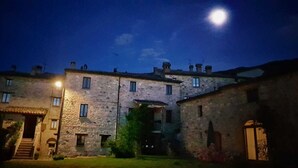 A stone building with multiple windows and a central entrance, illuminated by a single light source. - Appartamentino Rustico in Villa Maindi with garden use and free WiFi (Pennabilli)
