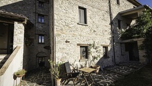 A stone building with a courtyard, a wooden table, and potted plants. - Appartamentino Rustico in Villa Maindi with garden use and free WiFi (Pennabilli)