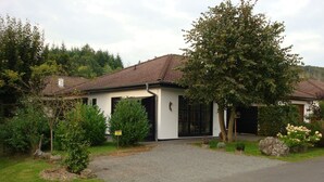 A two-story house with a tiled roof, a front porch, and a gravel driveway. - Luxury holiday home, 100 meters from forest, swimming pool nearby, 4 km from Edersee (Frankenau)